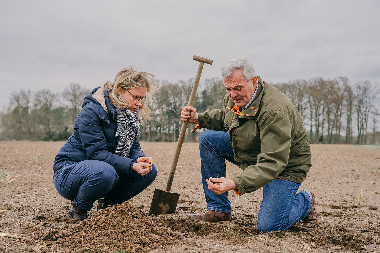 Zwei Menschen, die auf dem Feld hocken Zwei Menschen, die auf dem Feld hocken
