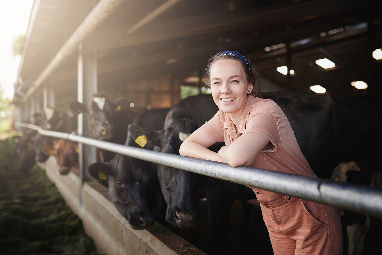 Landwirtin in einem Stall voller Kühe
