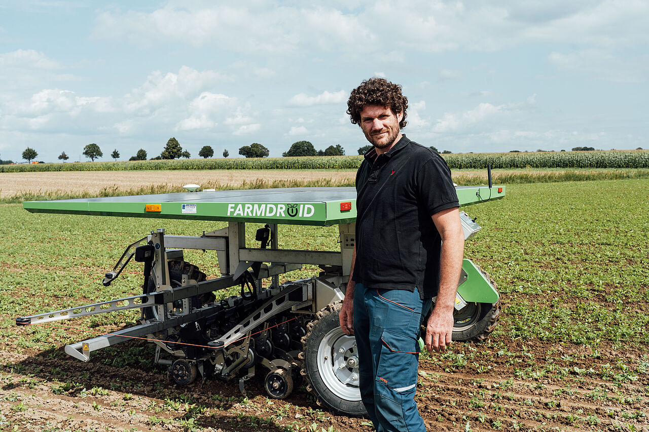Agrarroboter und Mann auf einem Feld Agrarroboter und Mann auf einem Feld